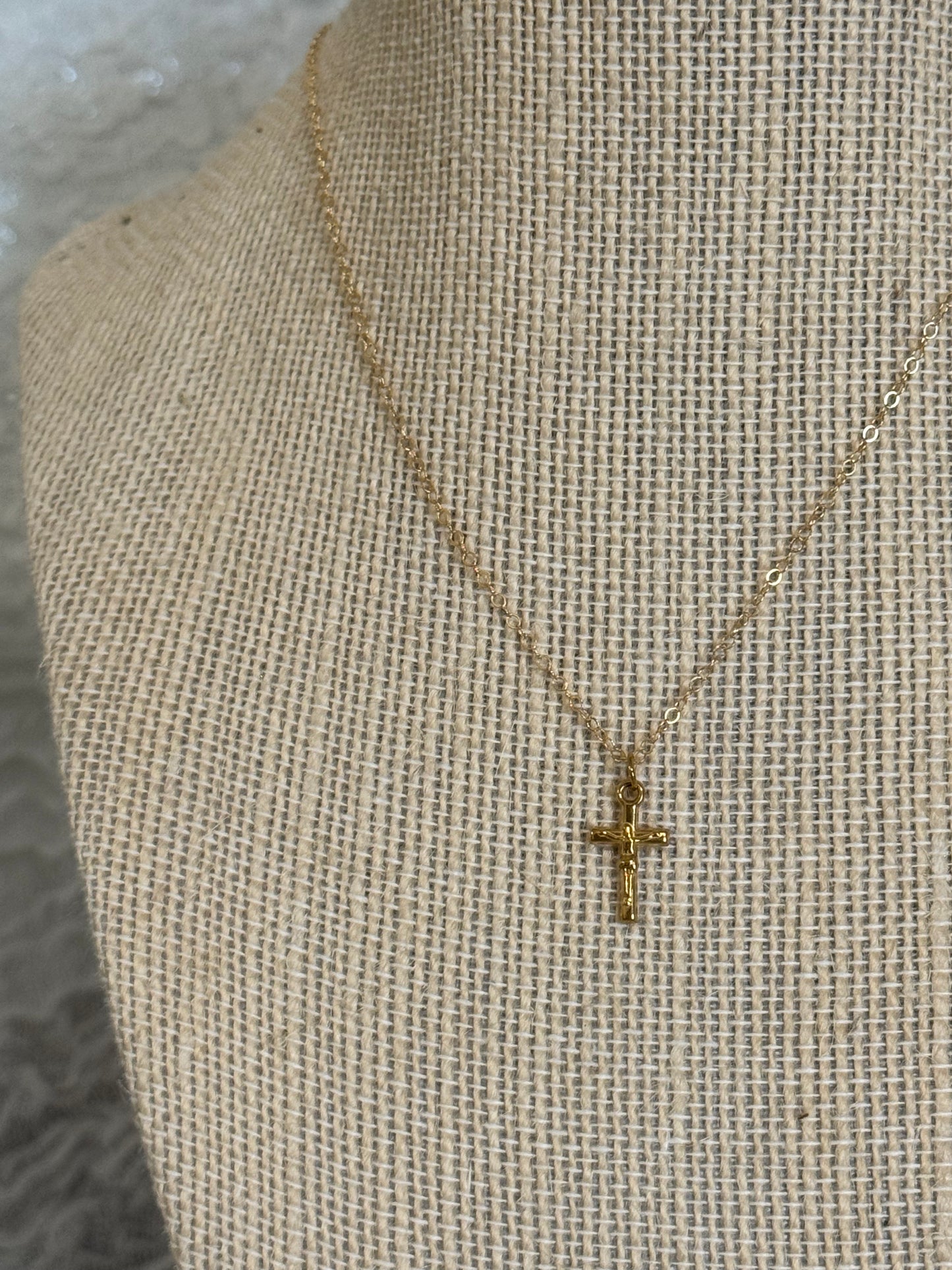 Close up of dainty gold-plated stainless steel crucifix pendant on 14k gold filled chain