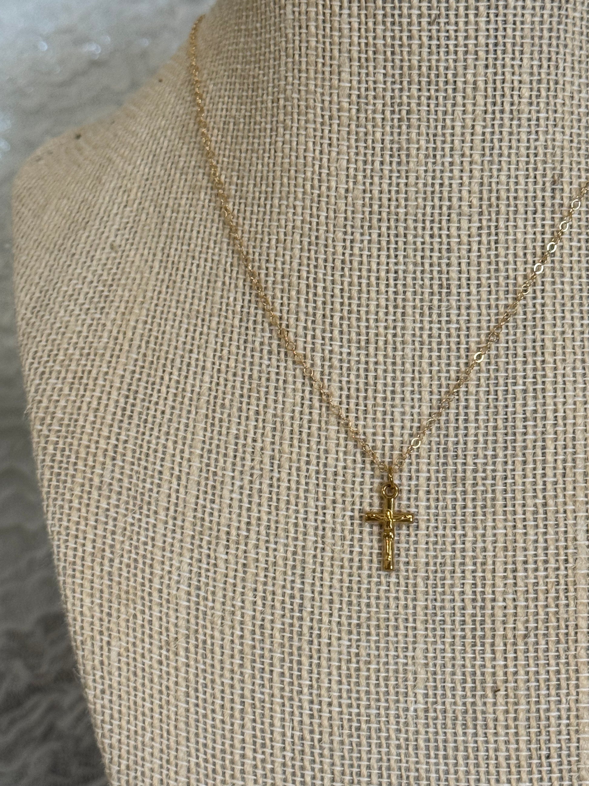 Close up of dainty gold-plated stainless steel crucifix pendant on 14k gold filled chain